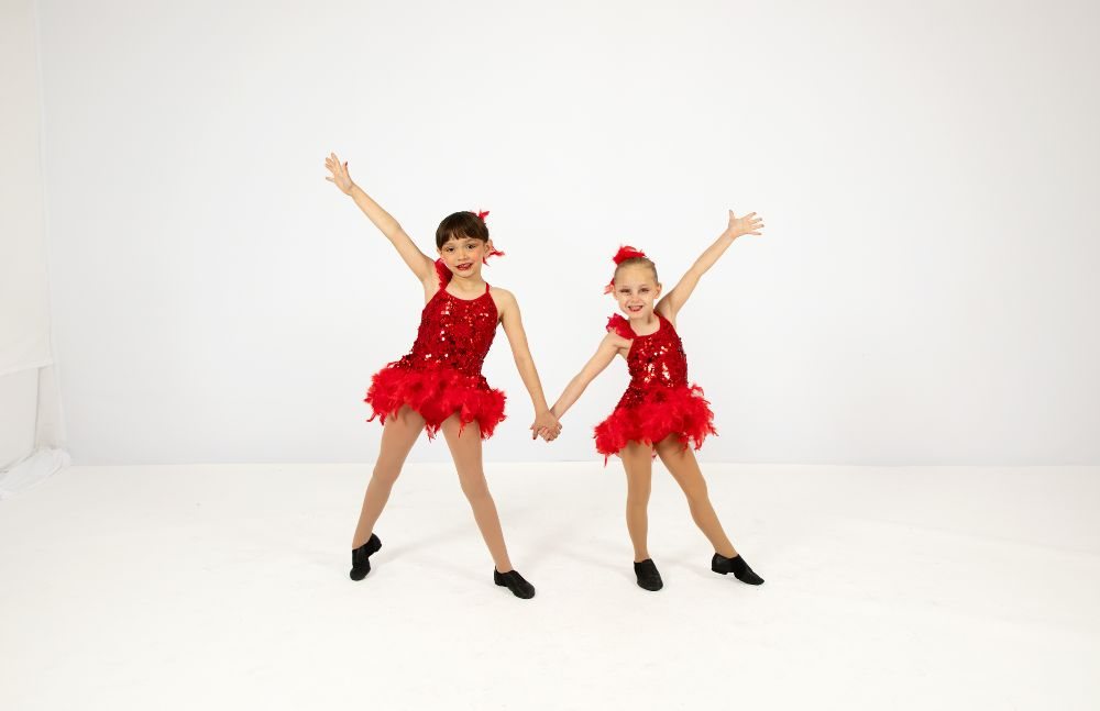 Two dancers in red costumes holding hands